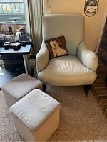 Photo of light-colored upholstered armchair with dog image cushion and two rectangular storage ottomans showing their condition, wear, and overall appearance in room setting.