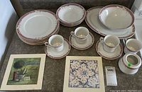 Full view of dishware set on table including plates, cups with saucers, serving pieces and trivets