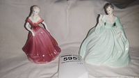 Photo shows two porcelain figurines, Amy in rose gown and Justine in green gown, with placard.