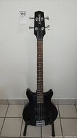 Front view of black 4-string electric bass guitar on stand