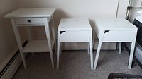 Three white Ikea nightstands - two are metal Selje models and one wood Hemnes model, shown side by side.