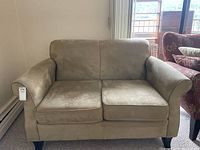 Front view of beige loveseat showing two seat cushions and two back cushions, with a throw cushion placed beside it.