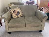 Green microfiber loveseat with two seat cushions and slightly curved arms, moderate wear visible. Includes a decorative throw pillow.