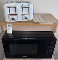 Microwave and toaster on wooden stand showing size and general condition