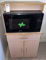 Microwave siting on the microwave stand, showing the microwave's front with control panel and door.