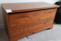 Front view of wood storage trunk showing flat top and front panel with wood grain.