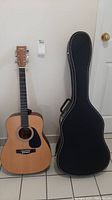 Yamaha Eterna EF35 acoustic guitar standing upright next to a black travel case with white stitching and a handle.
