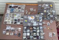 Three Plano boxes open showing multiple compartments filled with assorted jewelry making supplies, beads, metal findings, and wire.