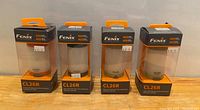 Four boxed Fenix CL26R rechargeable camping lanterns with visible price tags on packaging.