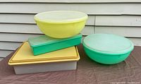 Four vintage Tupperware containers arranged on a surface, showing varying pastel colors and lids intact.
