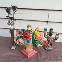 Photo showing all three items: the cast iron floral doorstop, metal rose flower vase, and colorful ceramic candle holder