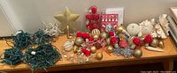 Photo showing all assorted decorations including the green Christmas lights, gold star tree topper, and various ball ornaments in red, gold, white, and beige.