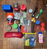 Wide top-down view of lot showing multiple camping and boating items including the orange Fox 40 kit, ropes, flashlight, pillow, stove, and various bottles.