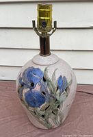 Side view of the lamp showing blue floral decoration and salt glaze finish.