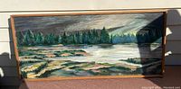 Front view of landscape oil painting on canvas inside a simple wooden frame. Shows trees, river, rocks, and sky.