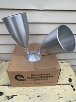 Two spun aluminum spotlight fixtures displayed on top of original 1970s cardboard box labeled 'Eclairage Columbia Lighting'