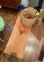 Flat cherry wood veneer sheet laid on wooden floor showing natural grain and a darker knot in the center