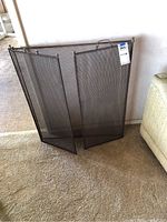 Front view of the folded three-panel metal fireplace screen showing the mesh and frame
