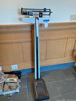 Full front view of the Health O Meter upright scale showing the base platform, upright column, sliding weight bar, and height rod.