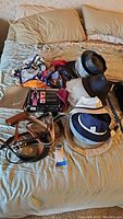 Photo showing the assorted scarves, hats, belts, and Muscle Minder boxed device on a bed.