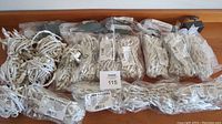 Sixteen new or mostly new bundled strands of S4 Professional Enchantment White Christmas Lights arranged horizontally on a table.