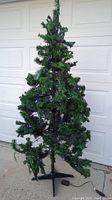 Full view of 6.5 foot artificial Christmas tree with purple lights, showing overall shape and metal stand.