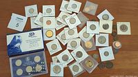 Wide shot of the collection including various coins in protective holders and loose coins on the table.