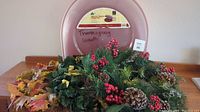 Three wreaths grouped in front of a pink plastic container labeled 'Thanksgiving Wreath'