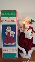 Photo showing vintage 26 inch animated Mrs Claus with lit candle next to original box
