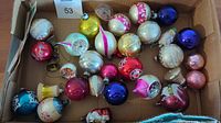 Full view of all vintage blown glass ornaments in a cardboard box showing variety of colors and designs.