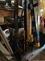 Overall view of the black folding engine crane frame with attached yellow hydraulic ram and chains