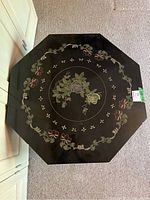 Top view of the octagonal tabletop showing the full floral pattern in black lacquer.