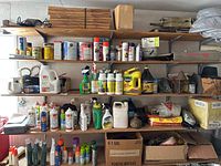 Overall view of multiple shelves containing assorted gardening supplies including sprays, insecticides, fertilizers, and tools.