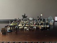 Wide view showing the main group of hand-painted vintage lead soldier figurines in various poses including infantry, cavalry on horseback, and artillery units with a cannon.