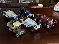Five vintage and classic 1:18 scale model cars displayed showing side and front profiles of each, with focus on detailed features and paint condition.
