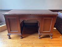 Front view showing carved details, recessed panels on the ends, and claw feet on casters.