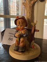 Front view of the vintage Hummel lamp showing the boy figurine holding the flower with the tree and bird behind.
