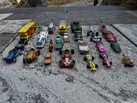 Overview of all 24 toy vehicles arranged in rows on stone surface