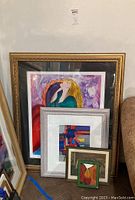 Four framed art prints leaning against wall, largest is signed serigraph 'Michelle' by Linda Le Kinff.