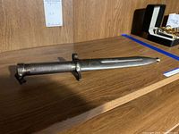 Side view of the metal bayonet showing textured handle and blade length