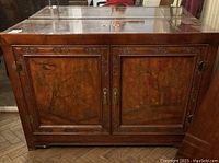 Front view of the ornate Bernhardt wooden buffet showing carved floral details and painted panels with scenes of nature and animals.
