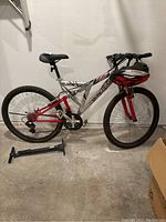 Side view of Mongoose mountain bike with helmet mounted on handlebar and floor pump beside it