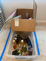 Photo showing clear plastic bin filled with assorted perfumes and colognes in various shaped bottles and sizes.