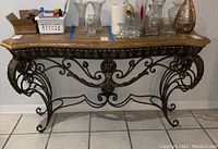 Front view of the console table showing faux marble top and decorative metal base with scroll and leaf designs.