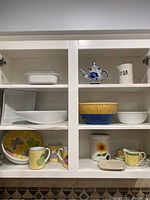 Full cabinet view showing upper and lower shelves holding various bowls, mugs, plates, and serveware.