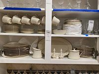 Shelf with cups, plates, bowls, cream and sugar, salt and pepper shakers, and serving platter showing the full set.