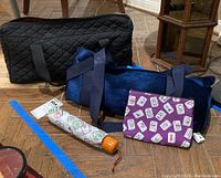 Two mahjong sets in carrying cases along with small pouch and umbrella laid on floor.