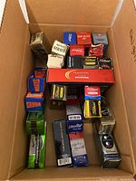 Overview of many unopened boxes and sleeves of golf balls in cardboard box