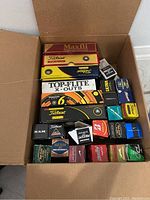 Top-down view of open cardboard box showing large retail golf ball boxes stacked and small sleeves along edges