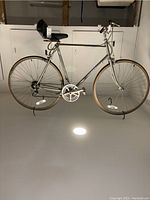 Full side view of chrome road bike hanging on a wall, showing frame, wheels, seat, and handlebars.